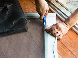 Hands of person cutting a new screen for an old door.