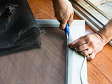 Hands of person cutting a new screen for an old door.