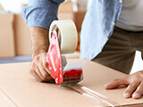 A man sealing a cardboard box with tape.