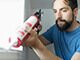 A man caulking an indoor window.