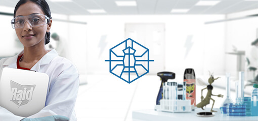 A smiling entomologist, wearing a lab coat and glasses, standing in a lab of the SC Johnson® Institute of Insect Science for Family Health